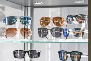 Multiple pairs of sunglasses on display in a glass case, showcasing different colors and styles.
