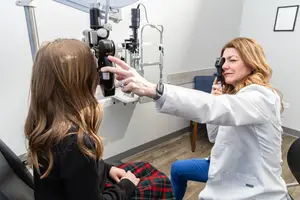 Woman doctor doing eye examination on a girl sitting on a chair