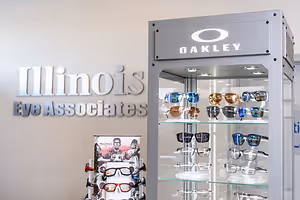 An Oakley sunglasses display with the brand name and Illinois Eye Associates logo on the wall in a retail setting