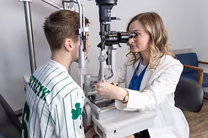 A man getting his eyes examined by a woman in a white coat