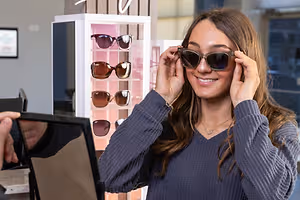 Woman in a store trying on sunglasses and smiling