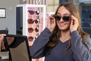 Woman in a store trying on sunglasses and smiling