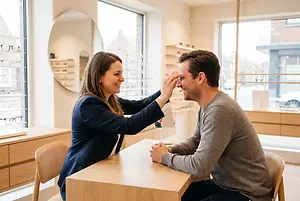 a woman adjusting a man's glasses in an optometrist's office