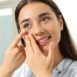 young girl holding contact lens near eye