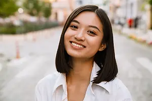 Portrait of a smiling woman in a white shirt on a street with blurry background