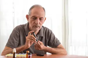 An older man pricking his finger to check blood sugar level