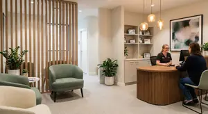 A woman talks to a woman at a reception desk in a medical facility.