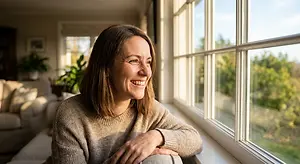 Woman looking out the window of a house and smiling