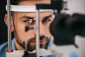 man looking into an eye exam machine