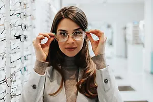 A woman is in a store looking at glasses.