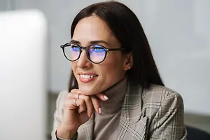Portrait of a smiling woman in a professional setting wearing glasses and a business suit