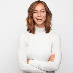 A woman wearing a white turtleneck shirt and smiling