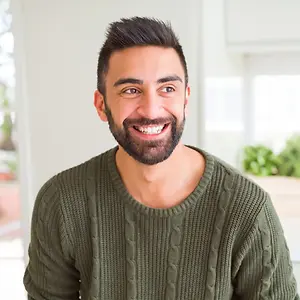 man wearing green sweater and smiling at the camera