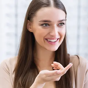 woman wearing a pair of glasses and showing the lens in her hand