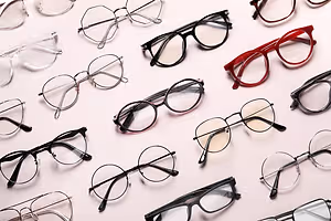 A collection of glasses with different colored frames and lenses displayed on a white surface.