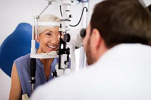 An optometrist examines a woman's eyes using a microscope.