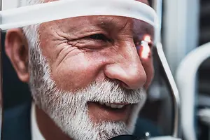 Elderly man with white beard and mustache getting an eye examination