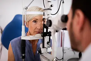 A woman is having her eyes examined by an optometrist in an optical shop.