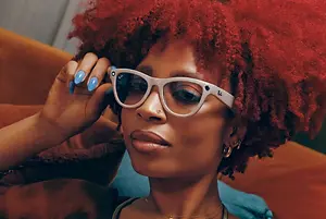 Woman wearing glasses with red curly hair and blue nail polish