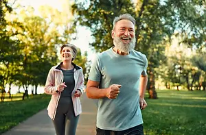 A man and a woman are jogging in a park on a sunny day.