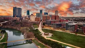 An aerial view of a city with many buildings, a river, and a bridge under a cloudy sky