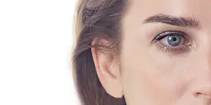 A woman's face with blue eyes, arched eyebrows, and eyeliner on the upper eyelid.