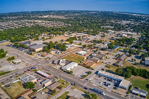 A top view of a city with many buildings and vehicles parked in the parking lot.