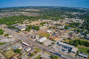 A top view of a city with many buildings and vehicles parked in the parking lot.