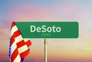 Green street sign with the word De Soto Texas on it and an American flag