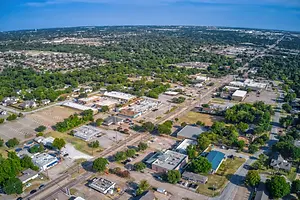 Aerial view of a town with many buildings and houses under a clear blue sky with clouds.