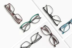 Five pairs of glasses of different colors are arranged on a white background