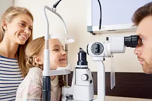 A little girl having her eyes examined by an optometrist in a clinic room.