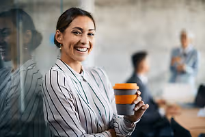 A woman holding a cup in an office with other people
