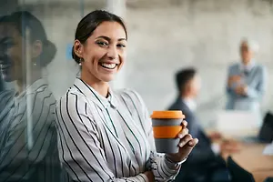 A woman holding a cup in an office with other people
