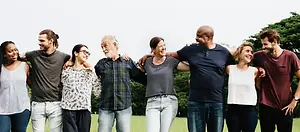 A group of people standing together in a park with trees in the background.
