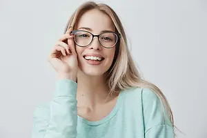 Woman wearing glasses and a blue shirt smiling for a photo