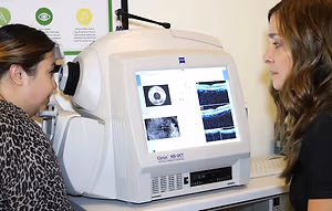 An OCT machine is shown with a woman peering at the screen.