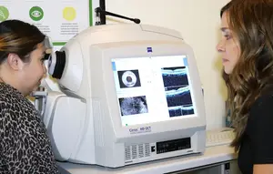 An OCT machine is shown with a woman peering at the screen.