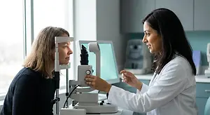 A woman is getting her eye examined by an eye doctor in a white coat