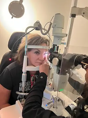 An adult woman is getting her eyes examined by another woman in a medical clinic.
