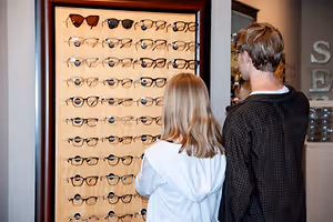 Two children are looking at a wall of glasses in a store.