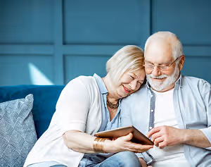 Senior couple watching something on a tablet in a room with blue walls