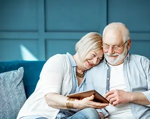 Senior couple watching something on a tablet in a room with blue walls