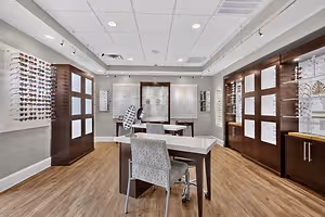 A closeup view of an empty eyeglasses shop with white ceiling lamps and wooden flooring.