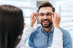 A man wearing glasses is having his vision checked by an optometrist