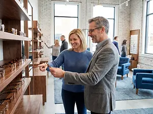A man and woman are looking at a shelf of glasses in a store.