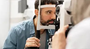 A man getting his eyes examined by a doctor using a slit lamp