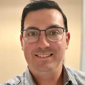smiling man wearing glasses and checkered polo shirt