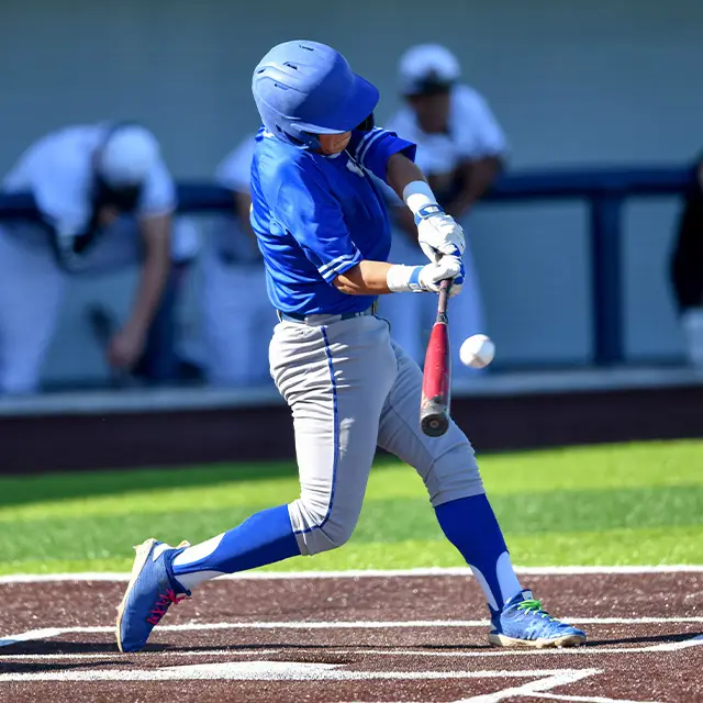 A baseball player in a blue jersey swings a bat at a baseball during a game