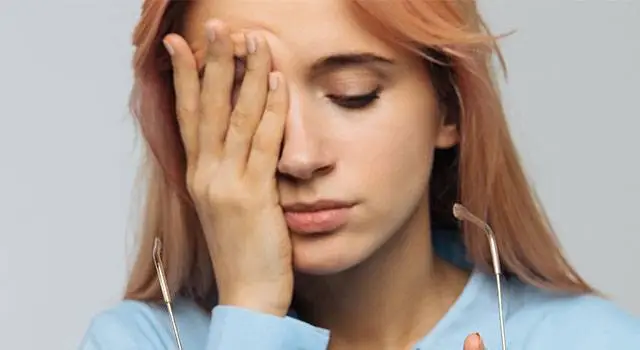 A woman with her eyes closed and her hand on her forehead